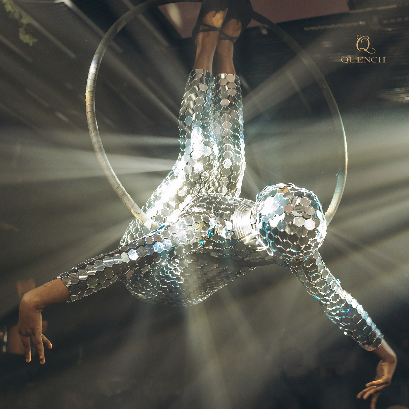An aerial hoop performer in mirrored silver