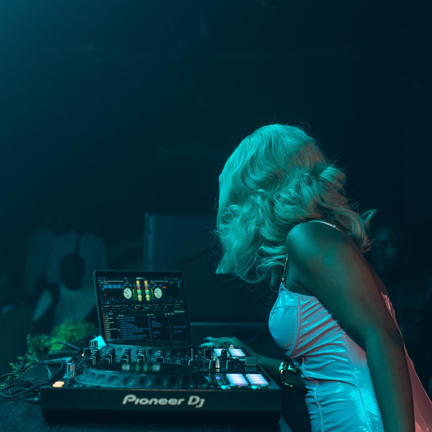 A DJ bent over the decks under blue light